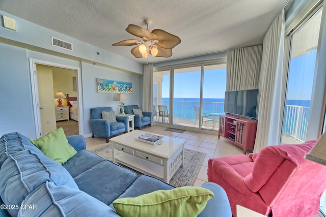 tiled living room featuring ceiling fan and a textured ceiling