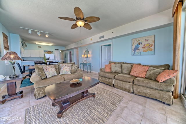 living room with visible vents, a ceiling fan, light tile patterned flooring, and a textured ceiling