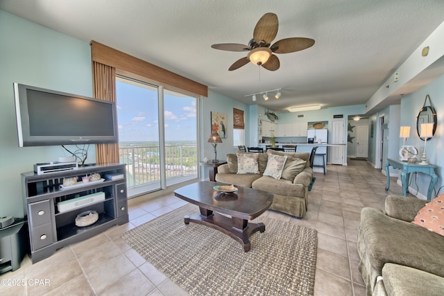 living room featuring rail lighting, a textured ceiling, a ceiling fan, and light tile patterned flooring
