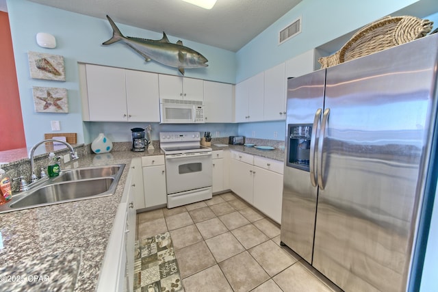 kitchen featuring white cabinetry, light tile patterned flooring, white appliances, and sink