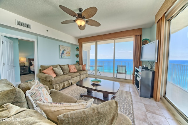 living room featuring visible vents, a ceiling fan, and a textured ceiling