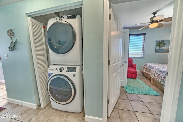 clothes washing area with light tile patterned floors, baseboards, ceiling fan, laundry area, and stacked washer / drying machine