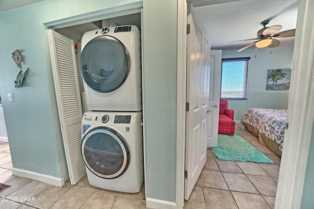 laundry area featuring light tile patterned floors, a textured ceiling, stacked washing maching and dryer, and ceiling fan