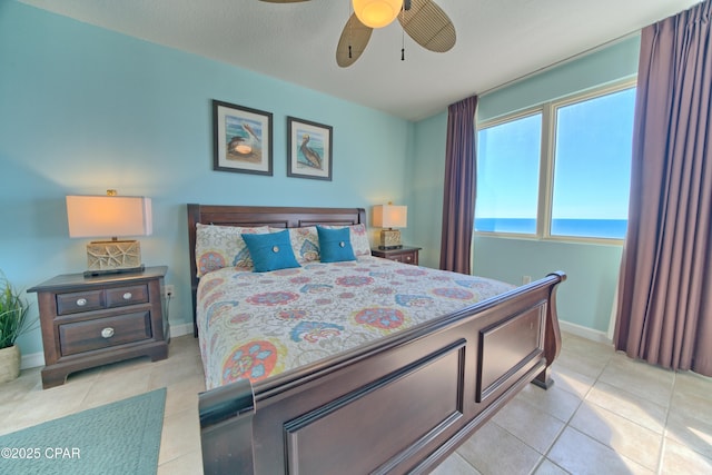 bedroom with light tile patterned floors, a water view, and ceiling fan