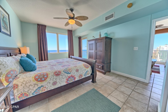 tiled bedroom featuring ceiling fan, a water view, and a textured ceiling