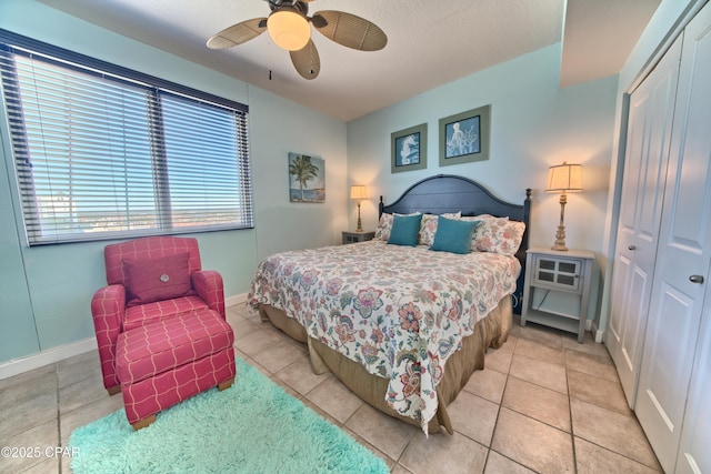 bedroom with a closet, baseboards, a ceiling fan, and light tile patterned flooring