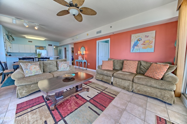 living room with a textured ceiling, ceiling fan, light tile patterned floors, and track lighting