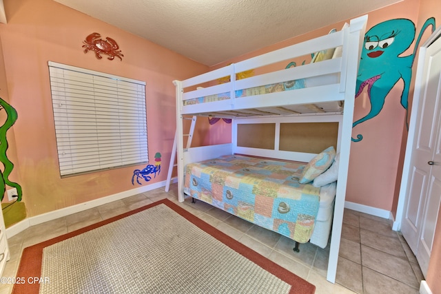 bedroom featuring a textured ceiling, baseboards, and tile patterned flooring