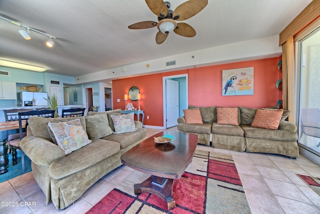 living room with light tile patterned floors, a textured ceiling, track lighting, and ceiling fan