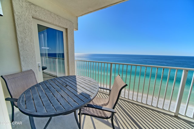 balcony with a water view and a view of the beach
