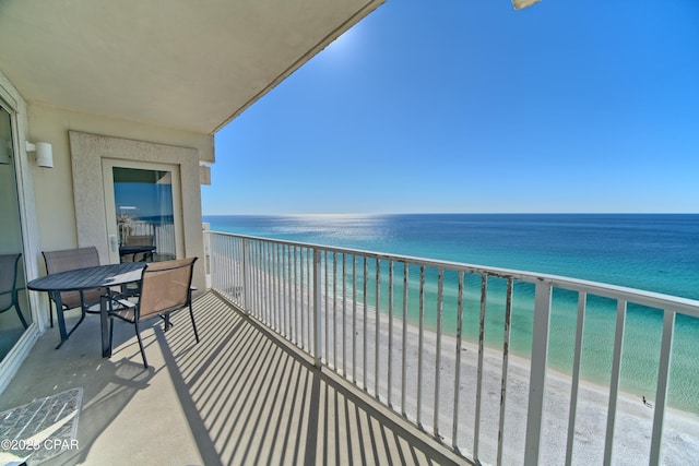 balcony with a water view and a view of the beach