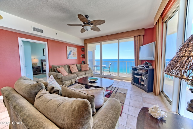 living room featuring ceiling fan, light tile patterned flooring, and a textured ceiling