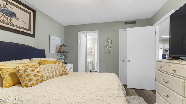 bedroom with dark wood-type flooring and connected bathroom