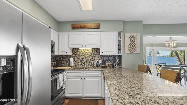 4271 Kingfish Ln Unit 271, Panama City Beach, FL 32408 - kitchen featuring white cabinetry, decorative backsplash, a sink, stainless steel appliances, and a notable chandelier