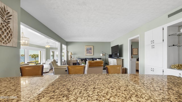 dining space with ceiling fan, a water view, and a textured ceiling