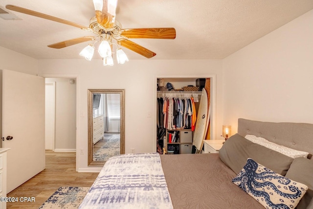 bedroom with ceiling fan, a closet, a textured ceiling, and light hardwood / wood-style flooring