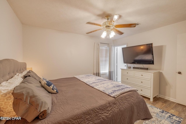 bedroom with ceiling fan, a textured ceiling, and light hardwood / wood-style flooring