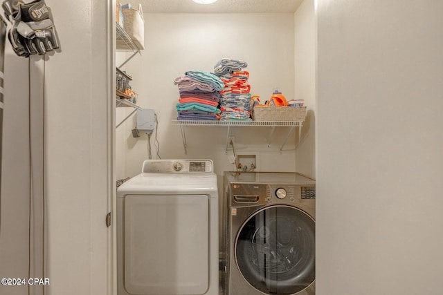 clothes washing area featuring washer and dryer and a textured ceiling