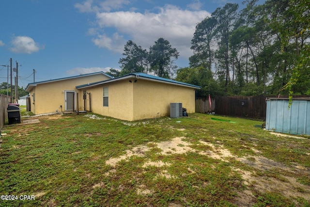 back of property with central air condition unit and a lawn