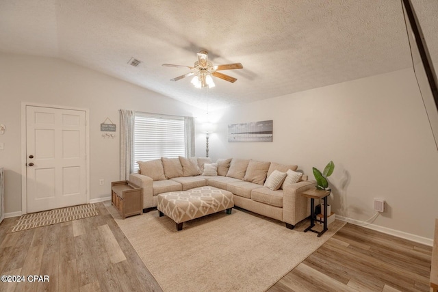 living room featuring ceiling fan, lofted ceiling, a textured ceiling, and light hardwood / wood-style flooring