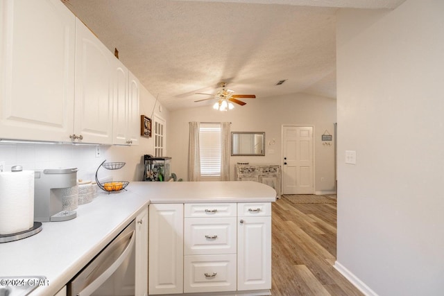 kitchen featuring stainless steel dishwasher, white cabinetry, kitchen peninsula, and vaulted ceiling