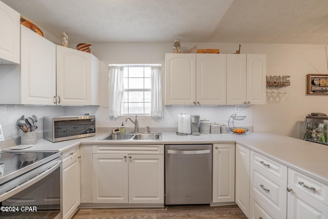 kitchen featuring hardwood / wood-style floors, sink, a textured ceiling, white cabinetry, and stainless steel appliances