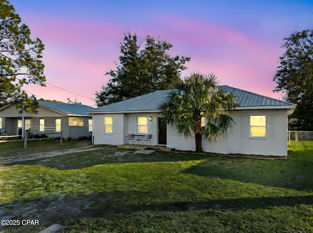 view of front of home with concrete block siding, a lawn, and metal roof