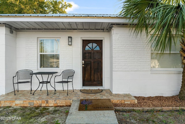 property entrance with brick siding and metal roof