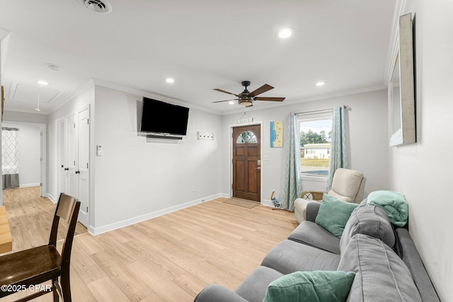 living area featuring attic access, baseboards, ornamental molding, and light wood finished floors