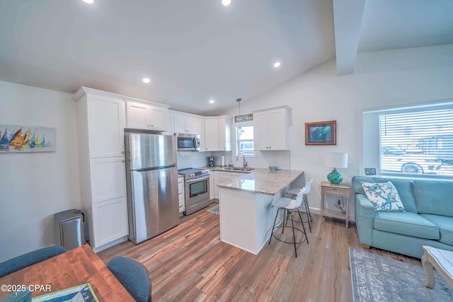 kitchen featuring appliances with stainless steel finishes, tasteful backsplash, decorative light fixtures, kitchen peninsula, and a breakfast bar area