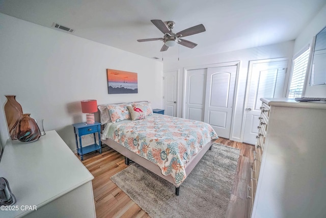 bedroom featuring light wood-type flooring, two closets, and ceiling fan