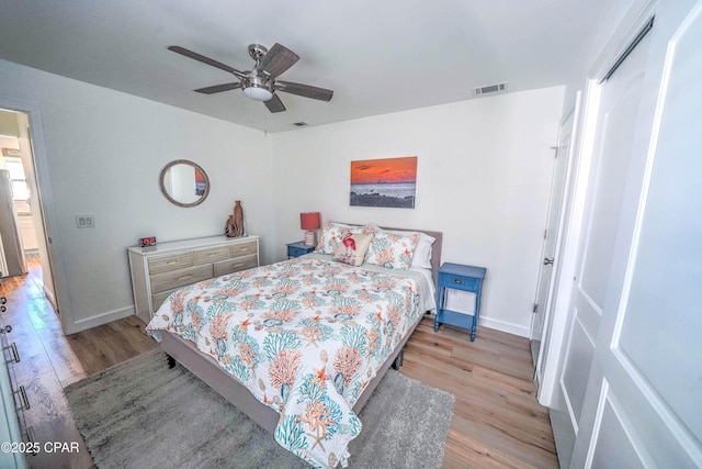 bedroom featuring stainless steel fridge, light hardwood / wood-style floors, and ceiling fan