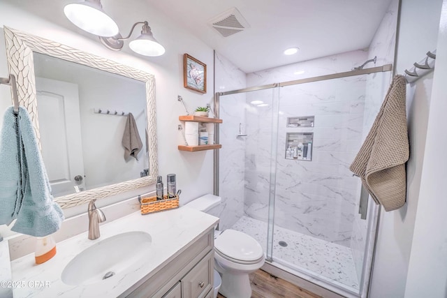 bathroom featuring vanity, toilet, a shower with door, and wood-type flooring