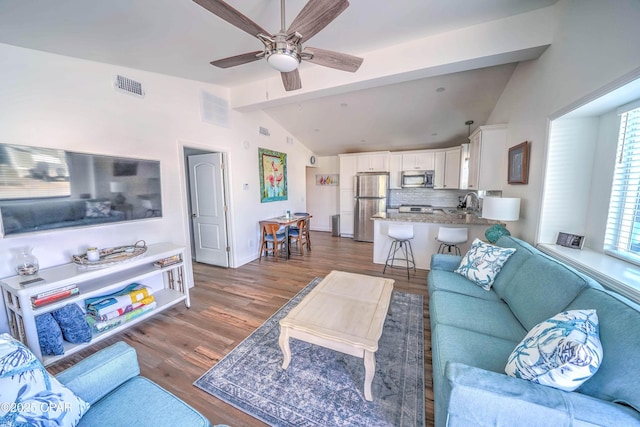 living room with lofted ceiling with beams, ceiling fan, sink, and dark wood-type flooring