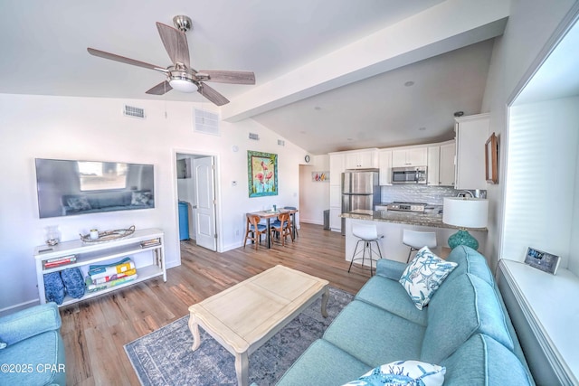 living room with lofted ceiling with beams, ceiling fan, and light wood-type flooring