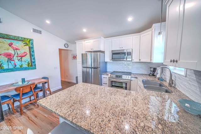 kitchen featuring white cabinetry, sink, kitchen peninsula, decorative backsplash, and appliances with stainless steel finishes