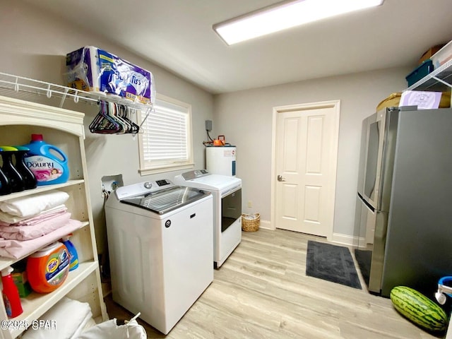 washroom featuring light hardwood / wood-style flooring, washer and dryer, and electric water heater