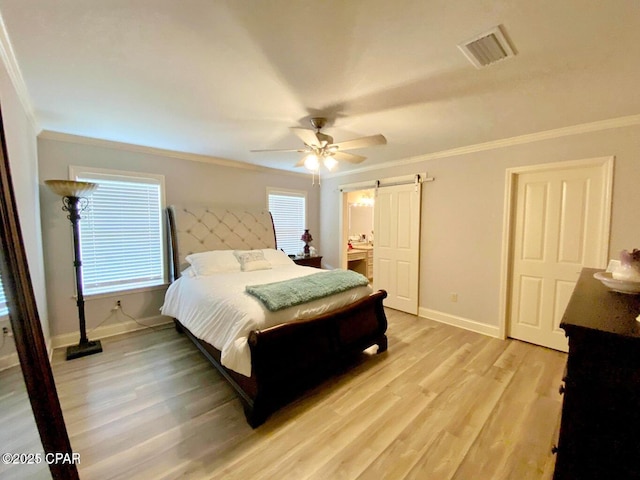 bedroom with ceiling fan, ornamental molding, a barn door, and light wood-type flooring