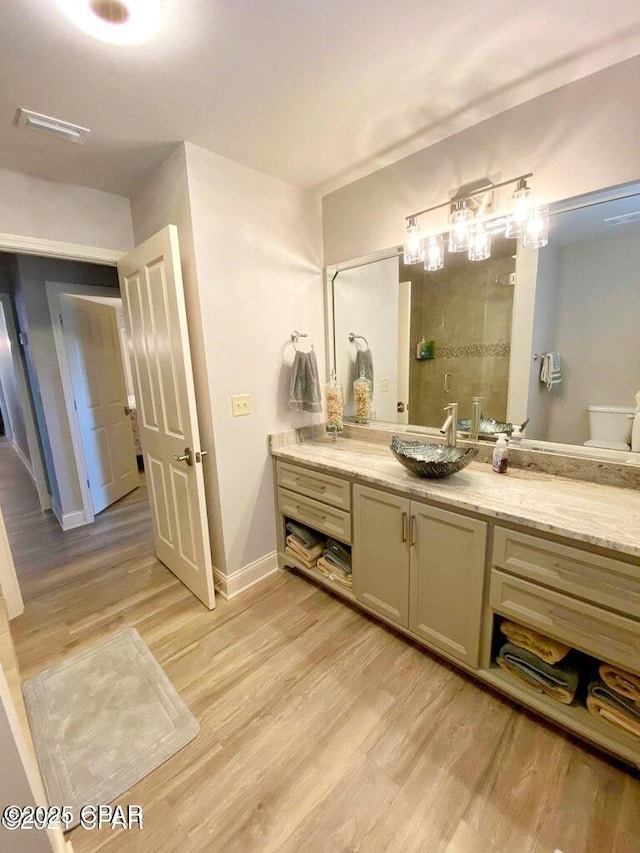 bathroom with wood-type flooring, a shower, and vanity