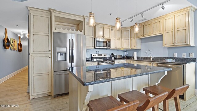 kitchen featuring hanging light fixtures, a center island, light hardwood / wood-style floors, sink, and appliances with stainless steel finishes