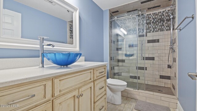 bathroom with toilet, vanity, hardwood / wood-style floors, and a shower with door