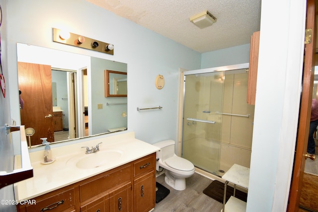 bathroom with vanity, wood-type flooring, an enclosed shower, and a textured ceiling