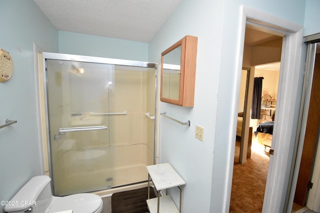 bathroom with toilet, a textured ceiling, and a shower with shower door