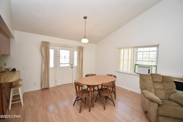 dining room with vaulted ceiling, cooling unit, and light hardwood / wood-style floors