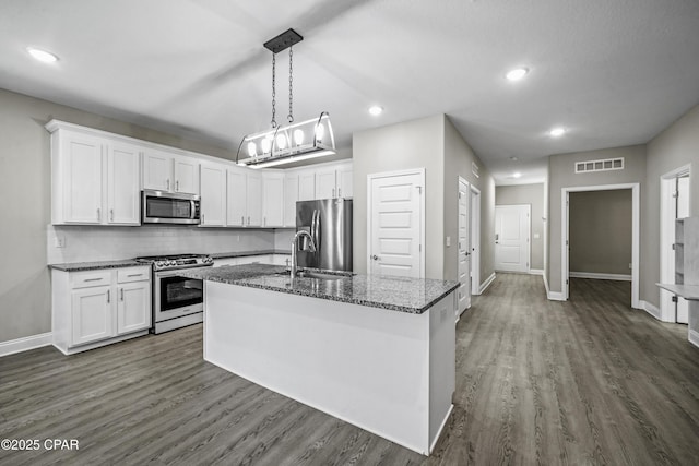 kitchen with white cabinets, appliances with stainless steel finishes, and a kitchen island with sink