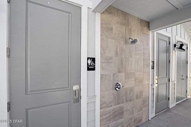 bathroom with tiled shower and concrete flooring