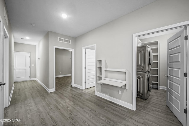 corridor featuring stacked washer / dryer and dark hardwood / wood-style flooring