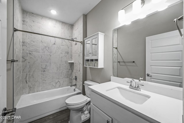 full bathroom featuring hardwood / wood-style flooring, tiled shower / bath combo, toilet, and vanity