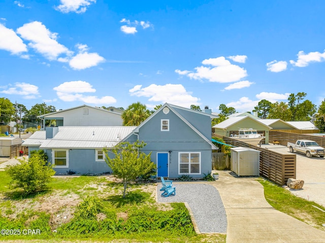 view of front of house with metal roof, a storage unit, fence, and stucco siding