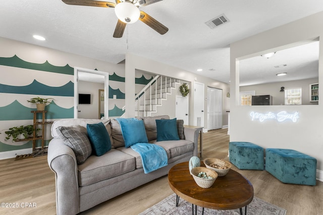 living room with stairway, baseboards, visible vents, and wood finished floors